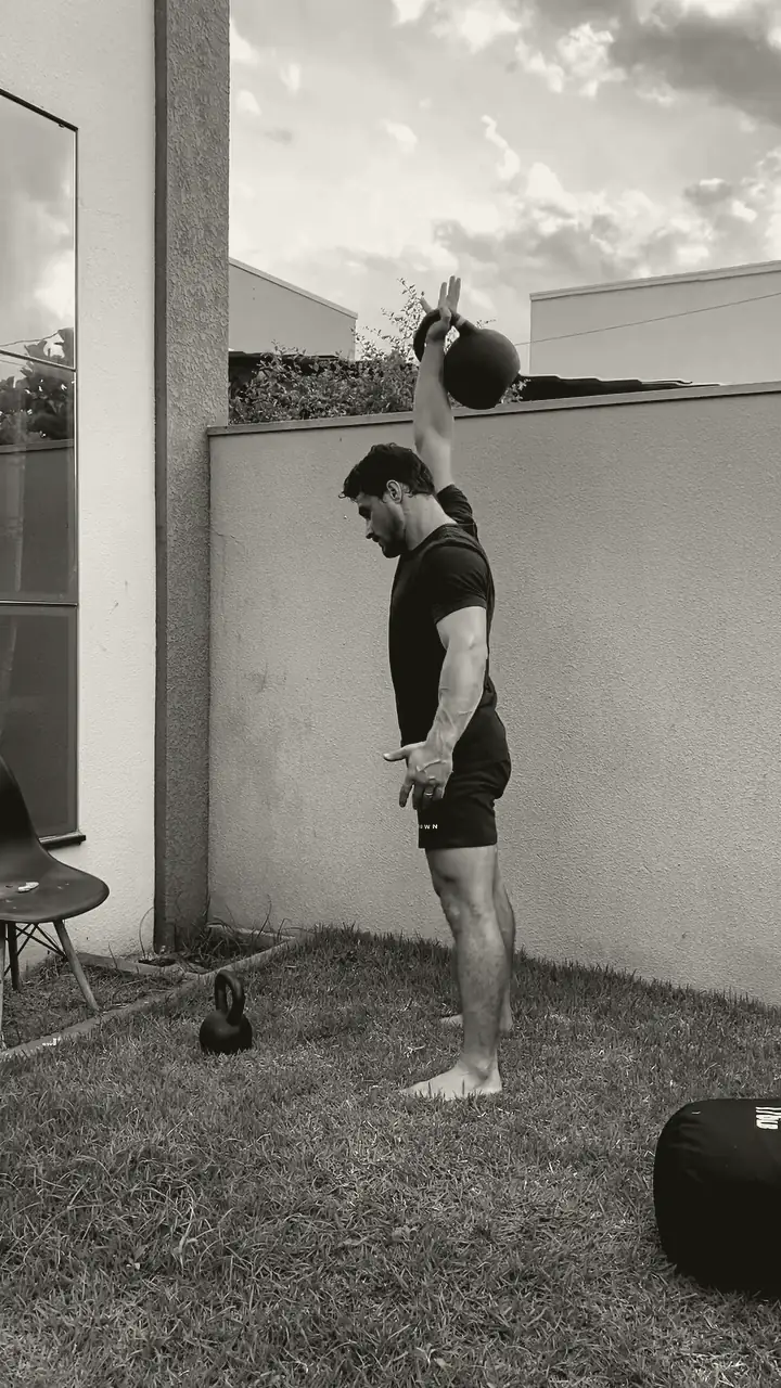 Lucas segurando o kettlebell acima da cabeça com o braço estendido